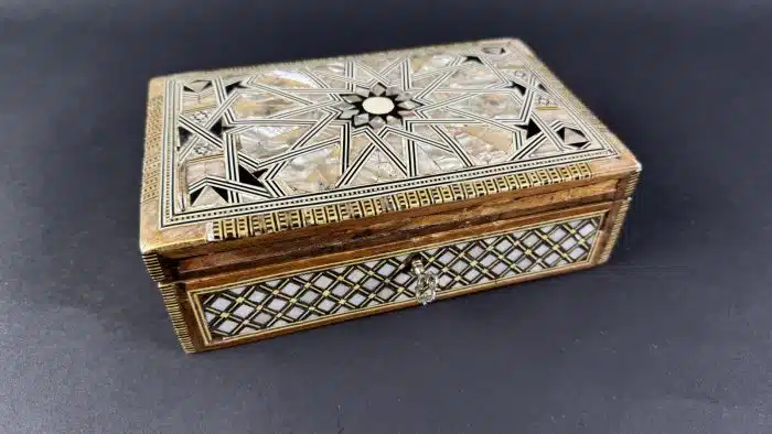 Schatulle, 20. Jahrhundert, Holzkassette mit ornamentaler Edelholz-, Bein- und Perlmuttmarketerie, innen in rotem Stoff staffiert, Scharnierdeckel, ca. 19x12 cm H 7cm, Alters- und Gebrauchsspuren